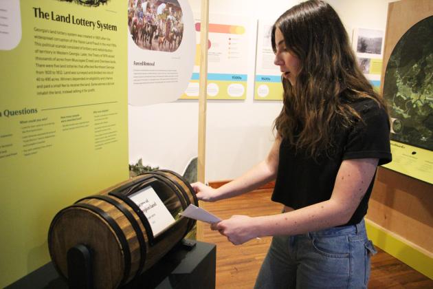 Grand Re-Opening attendee Olivia Weideman tries out a land lottery simulator at the Sautee Nacoochee History Museum. CARLY HENDERSON/WCN