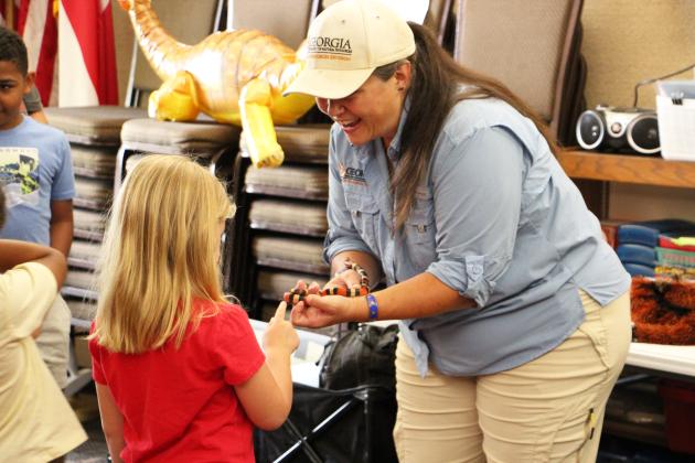 A young attendee pets a snake held by Kathy Church during the Cleveland Library’s “Creepy Crawlies” program. Children had the opportunity to interact with several animals during the presentation.