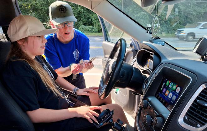 WCSO Officer Hannah Hammack demonstrates how officers use a tuning fork to properly calibrate radar equipment ensuring accurate readings before letting JLEA attendee Alex Staats try it herself.