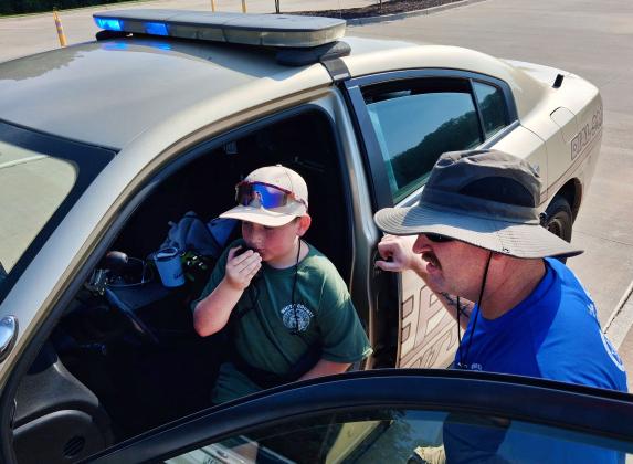 Officer Shawn Blinn of the White County Sheriff's Office instructs Brayden Martin on how to call in a traffic stop and how to approach the occupants of a vehicle once it is stopped.