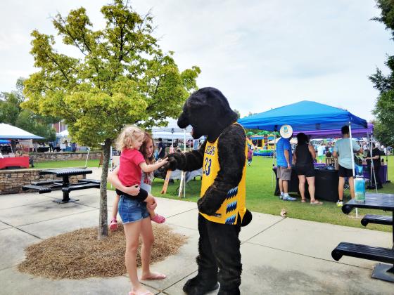 The Truett-McConnel University bear greets families to the Back-to-School Bash on Aug. 1 in Freedom Park. The bear shakes four-year old Ellie Woodbury's hand. Emma Seabolt, 12, of Cleveland, holds Ellie.