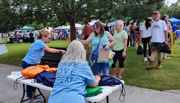 Volunteers from The Bridge Church hand out backpacks to students and students' families during the Back-to-School Bash. Tracy Pato is at left, Terry Mancini is at right.