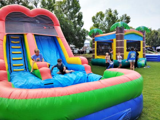 Children expend energy playing on the bounce slide and house during the Back-to-School Bash event.