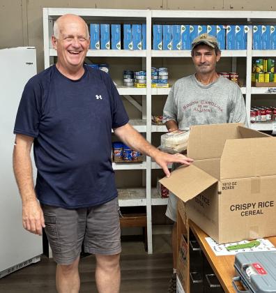 Volunteer Tim Skidmore, left, and Mike Butcher, director of the food pantry, separate food items to distribute.