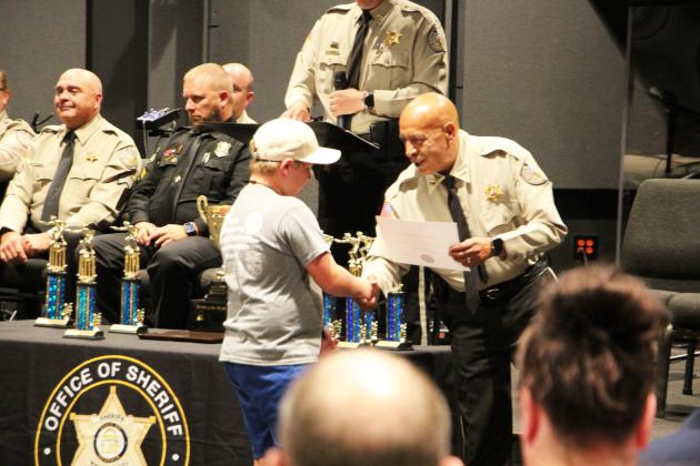 A cadet shakes hands with WCSO's Chief Deputy Gus Sesam after receiving his certificate for completing the camp.