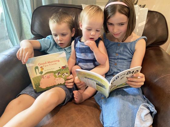 From left, Emmett, Mack and Eleanor Edlhuber enjoy a book received from Dolly Parton’s Imagination Library. They are the children of Joe and Stephanie Edlhuber of Cleveland. SUBMITTED