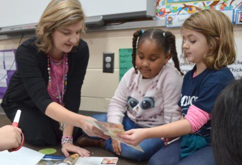 Jack P. Nix Elementary School first-grade teacher Teresa Beckman (from left) speaks with students Brooklyn Moss and Brelyn Austin Dec. 3 during an assignment about needs and wants. (Photo/Stephanie Hill)