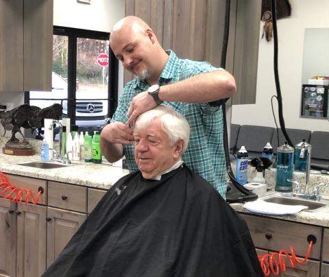 Pharmacist Ray Black sits for the first-ever haircut from Nathan McIntyre at Nate’s Barbershop, which opened Monday in Black’s new development, Cleveland Drug Plaza on West Kytle Street. Read more about the changes on 7A. (Photo submitted)