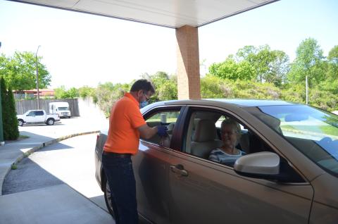 Terry Savoy places a meal in the car of Janelle and James Castleberry as part of the White County Senior Center’s drive-thru pick up service offered during the facility’s closure due to the COVID-19 pandemic. (Photo/Wayne Hardy)