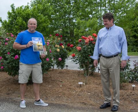Spring Lake Living cover contest winner Douglas Whiddon of Cleveland holds his photo of a sailboat in the sunset on Lake Lanier after Regional Publisher Alan NeSmith presented him with his prize. (Photo/Kimberly Brown)