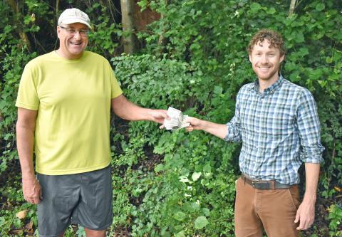 Matt Aiken, The Dahlonega Nugget publisher, hands Patrick Olmsted of Dahlonega, his prize money for winning The Mountain Traveler cover contest. (Submitted photo