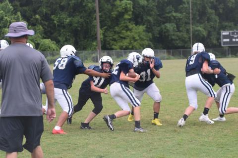 Colton Adam, left, and Malachi Russell, No. 31, try to bring down running back Jackson Krilla during a drill Monday morning at WCMS. (Photo/Mark Turner)
