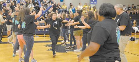 White County Middle School’s Dawn Powell runs through a lineup of fellow teachers on her way to celebrate with WCMS Principal Nara Allen during festivities a the school system’s back to school pep rally Aug. 2. (Photo/Wayne Hardy)