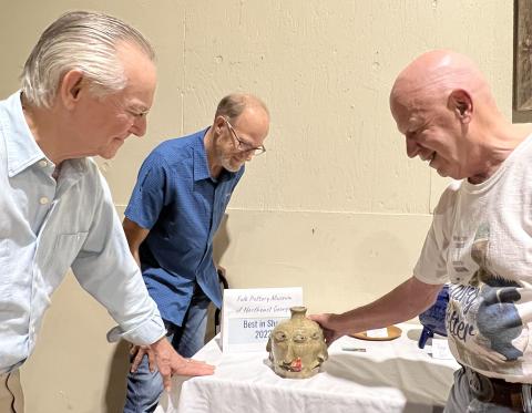 From left, Folk Pottery Museum trustees and judges John Luhn, Stewart Swanson and Bill House admire the “Best of Show” four-face jug created by Daniel Bollinger.