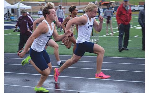 Cam Wilson, left, and Caysen Duvall sprint down the wet track during the 100-meter finals last week at the region meet at Warrior Stadium. (Photo/Mark Turner)