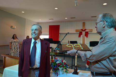 Andy Negra smiles as Alvin Seale presents him with a pecan birthday cake and the crowd sings “Happy Birthday.” (Photo/Samantha Sinclair)
