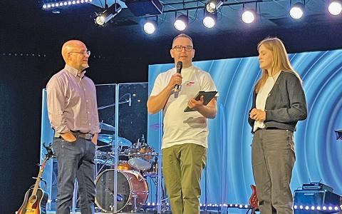 The Bridge Church Pastor Patrick Ballington listens as Igor Buben, joined by his wife Mariia, serves as a guest pastor at a recent service.  Buben was spreading awareness about the war in Ukraine and sharing the work his church, God’s Light Church in Lublin, Poland, is doing to help people affected. (Photo/Lauren Filbeck)