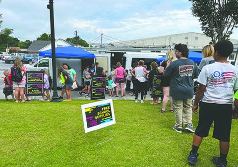 Elementary, middle and high school students and their parents eagerly wait in line for their free school supplies at last year’s event. (File photo)