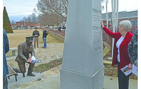 Terri Crumley brushes her hand over the side of the White County War Memorial where her brother’s name is etched as the new Families of the Fallen monument faces the memorial. (Photo/Samantha Sinclair)