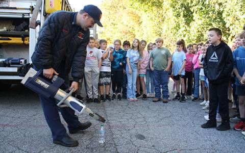 Battalion Chief Josh Taylor gives a demonstration of the jaws of life on a water bottle, much to the amazement of the crowd. (Photo/Eric Tiongson)