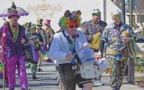 Walt Snyder pounds the drum while leading the parade goers from location to location. (Photo/Basil Ray)