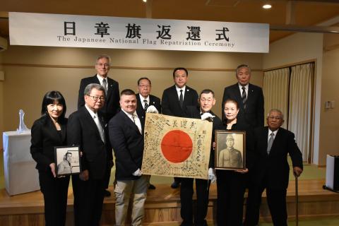 Chris Dorsey, third from left, holds a Yosegaki Hinomaru, a Japanese flag sent to battle with Japanese soldiers during WWII. He’s accompanied by family members of the soldier, Fumio Kudo, and other supporters of the project that returns items to families of soldiers. An unidentified woman holds a picture of Col. Thomas Rogers, great-grandfather of Dorsey, who had the flag for decades. (Photo/submitted)