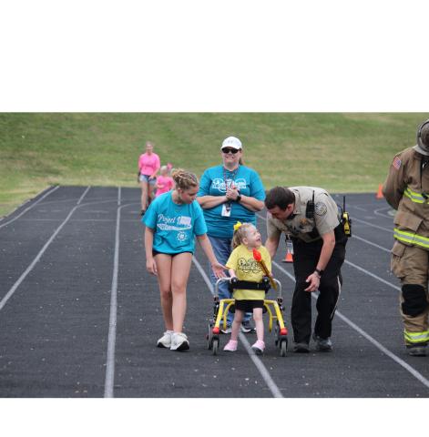 Torch Runner Carter Bresnahan shares a laugh with Student Resource Offier Travis Ramey during the last portion of the torch run for the Opening Ceremony of the Special Olympics. Also shown are, left, athlete buddy Sophia Pruitt and Dawn Grindle.