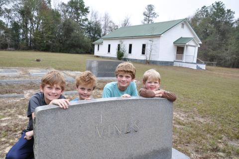 In 2017 four of our eight grandchildren visited the graves of their ancestors at Pilgrims Home Free Will Baptist Church on Hwy. 91 in Baker County, Georgia. The Wilsons are, from left, Hayes, Henry, Wyatt and Smith. They are posing by the granite tombstone of my mother’s parents, Howell and Essie (Nanny) Vines. (Photo by Dink NeSmith)