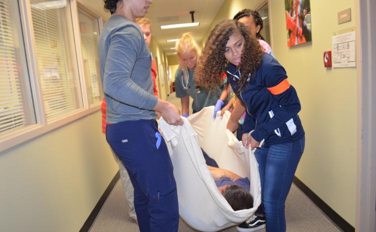 From left, Joshua Thereur, Caleb Johnston, Taylor Brown, Amaya Cartwright and Brittany Linley lift Ethan Conners as they prepare to carry him down the stairs to be transported. (Photo/Stephanie Hill)