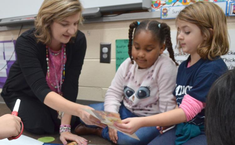 Jack P. Nix Elementary School first-grade teacher Teresa Beckman (from left) speaks with students Brooklyn Moss and Brelyn Austin Dec. 3 during an assignment about needs and wants. (Photo/Stephanie Hill)