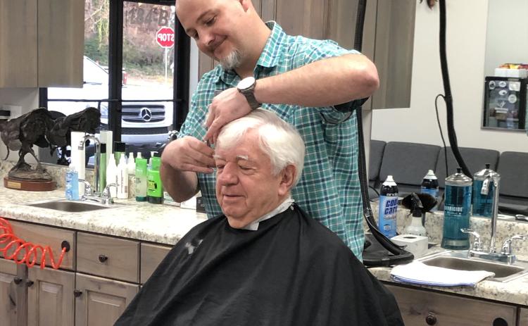 Pharmacist Ray Black sits for the first-ever haircut from Nathan McIntyre at Nate’s Barbershop, which opened Monday in Black’s new development, Cleveland Drug Plaza on West Kytle Street. Read more about the changes on 7A. (Photo submitted)