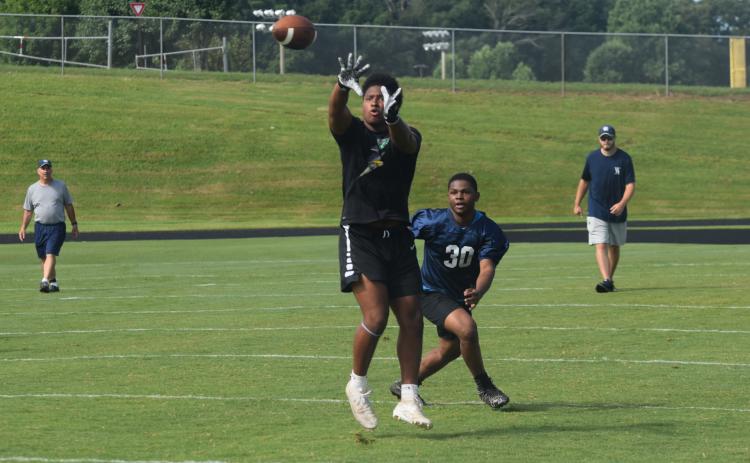 Running back Zion McMullen hauls in a pass in front of linebacker Xzavier Whitlock during a 7-on-7 session last week. (Photo/Mark Turner)