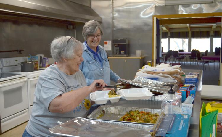 Judy Winski, left, and Melody Thomason prepare a meal to go during First Presbyterian Church of Cleveland’s inaugural First Lunch Day event on April 5. (Photo/Wayne Hardy)