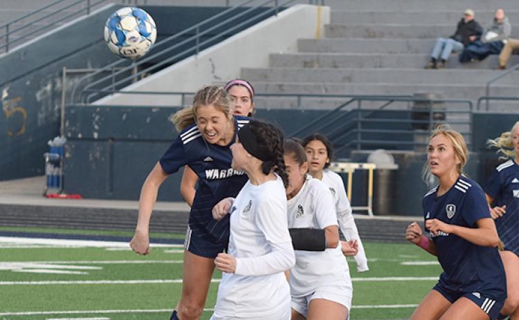 White County's Callie Armour, left, heads a ball off a corner kick during the Lady Warriors' win over West Hall Tuesday at Warrior Stadium. (Photo/Mark Turner)