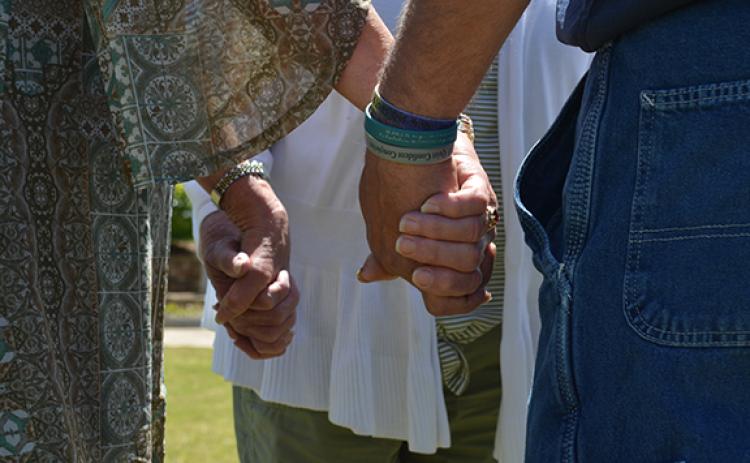 Gloria Hughes, Kim Fletter and Hal Miller join hands as they pray for each other during National Day of Prayer at Freedom Park. (Photo/Samantha Sinclair)
