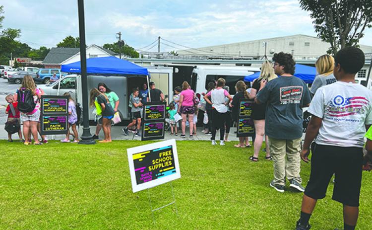 Elementary, middle and high school students and their parents eagerly wait in line for their free school supplies at last year’s event. (File photo)