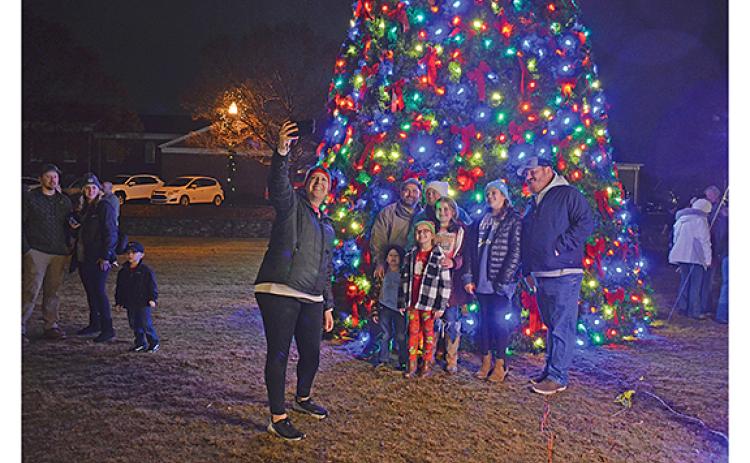 Lori Pressley takes a photo of herself and her family, the Schmidt Pressley family, after the tree is lit in Freedom Park. (Photo/Samantha Sinclair)