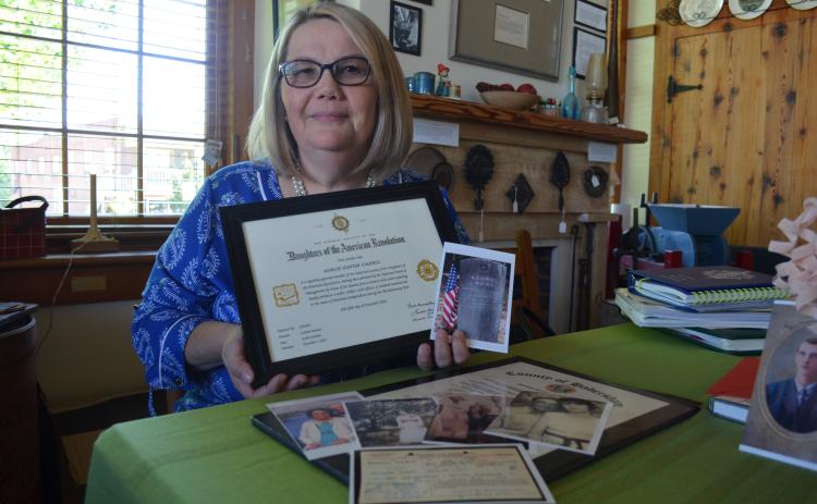 Marcie Gunter Caudell holds her certificate of membership in Daughters of American Revolution, along with a photo of the grave site of Aaron Boggs, her patriot. (Photo/Samantha Sinclair)