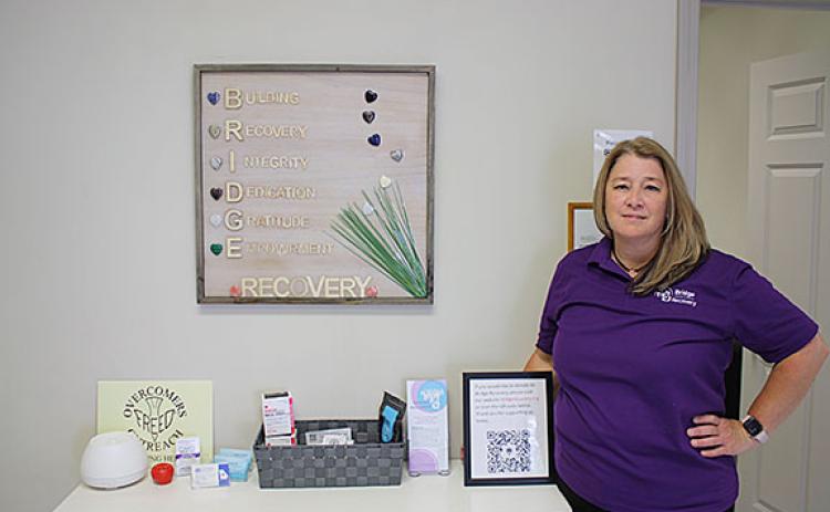 Shelley Sidders poses with a framed piece of art that spells out the B.R.I.D.G.E acronym in Bridge Recovery. (Photo/Eric Tiongson)
