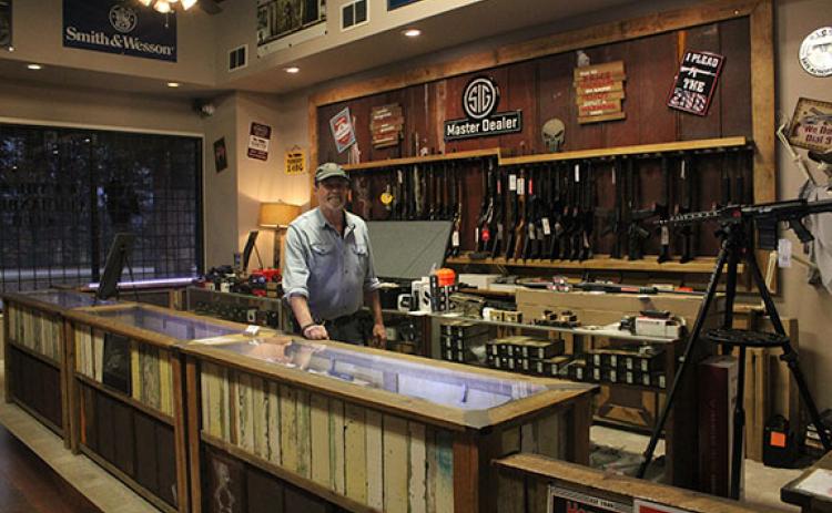 Mike Carter stands among the firearms in his store, Gun Commanders. Gun Commanders has been around for 11 years, and Carter hasn’t seen as much excitement this year as he did during the 2020 election. (Photo/Hannah Caudell)