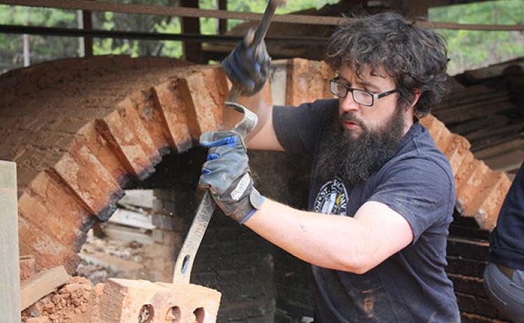 Daniel Bollinger chips away at mortar holding the kiln’s bricks together, digging to pull out any non-eroded bricks he can. (Photo/Eric Tiongson)