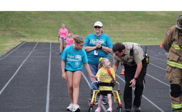 Torch Runner Carter Bresnahan shares a laugh with Student Resource Offier Travis Ramey during the last portion of the torch run for the Opening Ceremony of the Special Olympics. Also shown are, left, athlete buddy Sophia Pruitt and Dawn Grindle.