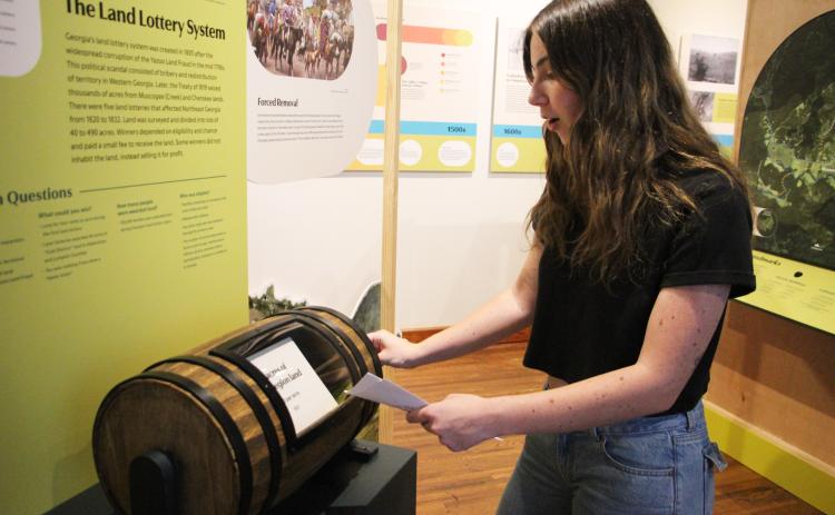 Grand Re-Opening attendee Olivia Weideman tries out a land lottery simulator at the Sautee Nacoochee History Museum. CARLY HENDERSON/WCN
