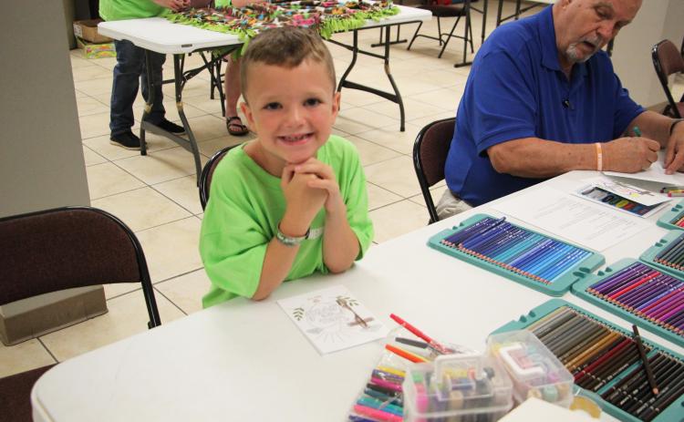 Atticus Miles writes an encouragement card to be included in a comfort backpack for a child entering foster care during the Love Your Neighbor event at Helen First Baptist Church on July 11. PHOTOS BY CARLY HENDERSON/WCN