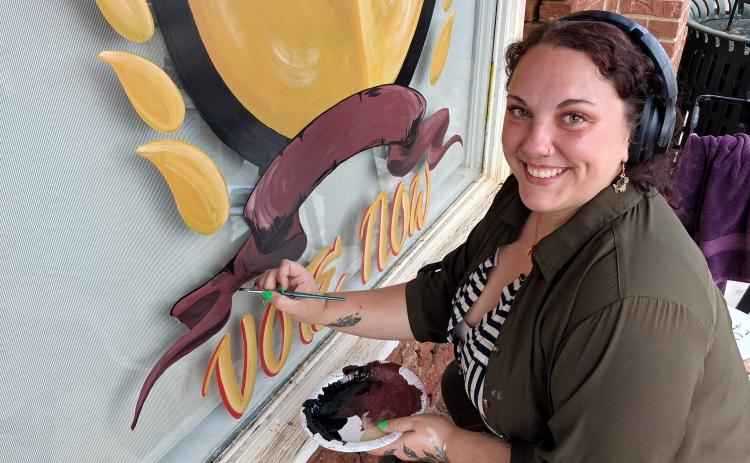 Heather Moon puts the finishing touches on the 2026 Readers’ Choice Awards emblem on the front window of the White County News office. ERIN ETRIS
